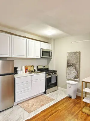 a kitchen with white cabinets and a stainless steel refrigerator at Yale Casa Verde Studio in New Haven