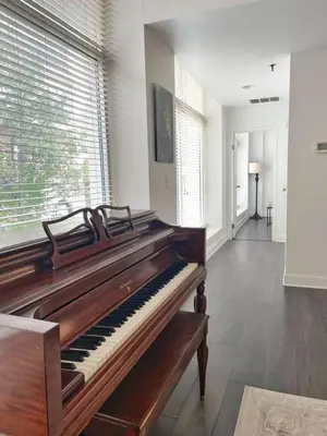 a piano in a room with a large window at Yale Modern Downtown Chateau in New Haven