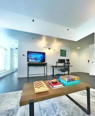 a living room with a table and a tv at Yale Modern Downtown Chateau in New Haven
