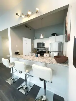 a kitchen with white chairs and a counter top at Yale Modern Downtown Chateau in New Haven