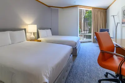 a hotel room with two beds and a desk and a chair at Windrose on Hudson in Ossining