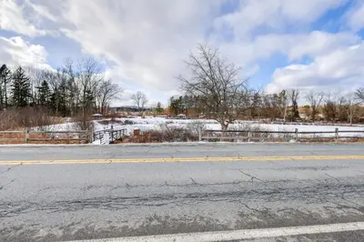 an empty road with a fence and snow at 9 Mi to Lake George Village Home in Queensbury in Queensbury