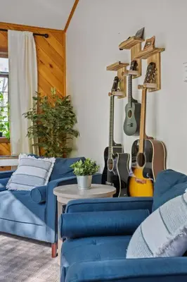 a living room with two blue couches and guitars on the wall at Mountain Oasis Hot Tub Game Room Fire Pit in Pocono Summit