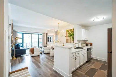 a kitchen with white cabinets and a living room at The Gallery in Downtown Stamford in Stamford