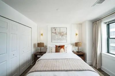 a white bedroom with a large bed with two tables at The Gallery in Downtown Stamford in Stamford