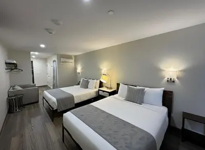 a hotel room with two beds and a couch at Nova Hotel JFK in Hillside