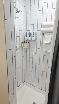 a bathroom with a shower with white tiles at Nova Hotel JFK in Hillside
