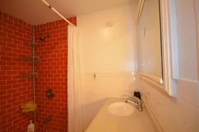 a bathroom with a sink and a shower with red tiles at MOTEL House in Newark