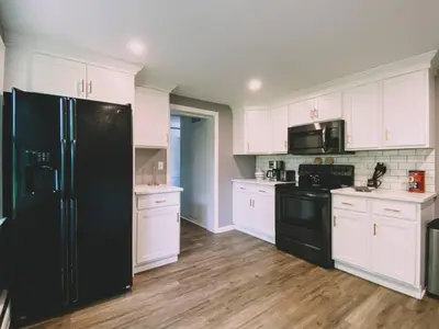 a kitchen with a black refrigerator and white cabinets at Centrally Located - 3 Br House in Southington