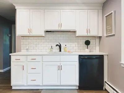 a kitchen with white cabinets and a black dishwasher at Centrally Located - 3 Br House in Southington