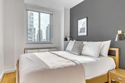 a white bedroom with a large bed and a window at UWS 1br w doorman elevator nr Central Park NYC-372 in New York