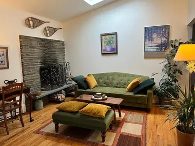 a living room with a green couch and a fireplace at Charming home - views of Hunter Mountain slopes in Hunter