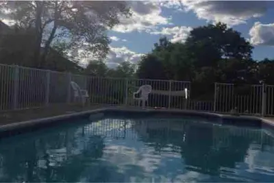 a swimming pool with two chairs next to a fence at Charming home - views of Hunter Mountain slopes in Hunter