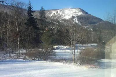a snowy field with a mountain in the background at Charming home - views of Hunter Mountain slopes in Hunter