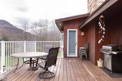 a wooden deck with a table and a grill at Charming home - views of Hunter Mountain slopes in Hunter