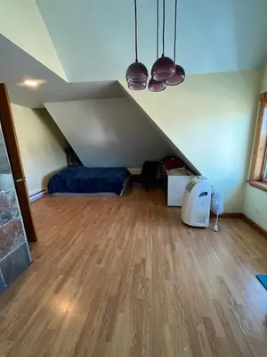 a attic room with a bed and a hard wood floor at Grand 2BR near MetroNorth with easy parking in Yonkers