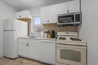 a kitchen with white cabinets and a stove and a microwave at Spacious 3-Bedroom Apartment near NYC - 15min to Times Square, Empire State Building, Central Park, Statue of Liberty in Jersey City