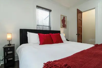 a bedroom with a large white bed with red pillows at Fully-stocked Kitchen, AC, WiFi, WD, Near Baseball and Downtown in Oneonta