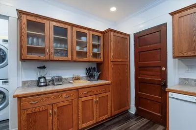 a kitchen with wooden cabinets and a washer and dryer at Fully-stocked Kitchen, AC, WiFi, WD, Near Baseball and Downtown in Oneonta