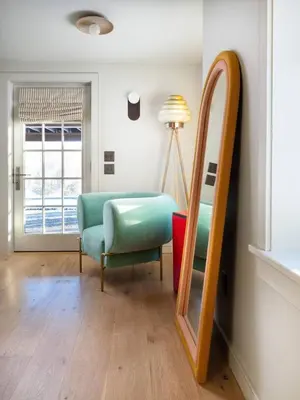 a living room with a mirror and a chair at Post & Beam - Stunningly Designed Luxury Home with Pool & Hot Tub in Pine Plains