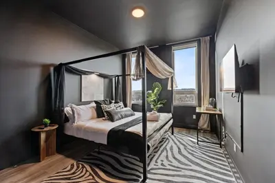 a bedroom with a canopy bed and a rug at Cozy 1 King BR, Gym, Free Parking, 8mins Train in East Orange