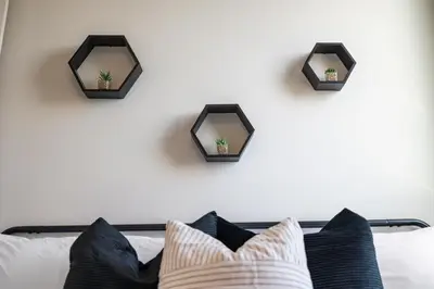a wall with three mirrors above a bed with pillows at 2BR, King Bd, Free Prkn, Gym, NYC View, 8min Train in East Orange