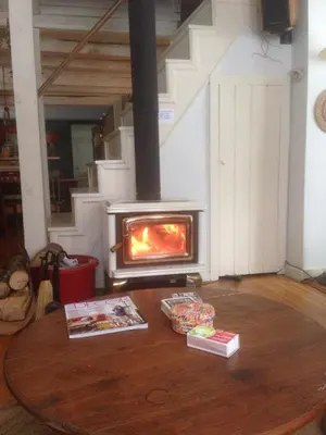 a fireplace in a living room with books on a table at Charm at the foot of the Berkshires in Hillsdale