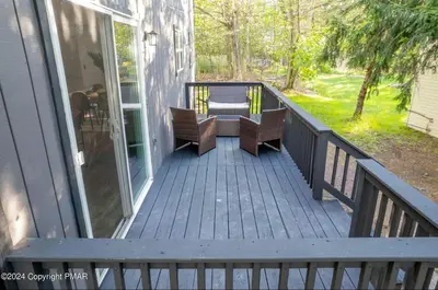 a deck with two chairs on a house at Whimsical Wilderness Lodge in Tobyhanna