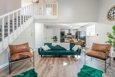 a living room with a green couch and two chairs at Whimsical Wilderness Lodge in Tobyhanna
