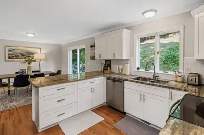 a kitchen with white cabinets and a sink and a table at Main Street Stay Westport in Westport