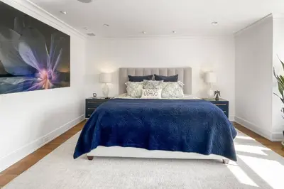 a bedroom with a blue bed and a painting on the wall at Waterside Haven in Branford