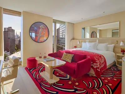 a bedroom with a large bed and a red couch at Faena New York in New York