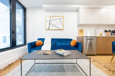 a living room with a blue couch and a table at 202 New Condo 1BR in Prime Greenpoint in Brooklyn