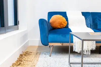 a blue couch in a living room with a table at 202 New Condo 1BR in Prime Greenpoint in Brooklyn