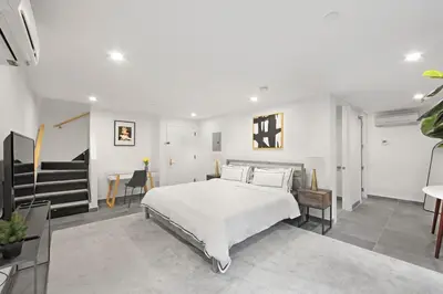 a bedroom with a white bed and a staircase at 149 Green Street in Brooklyn