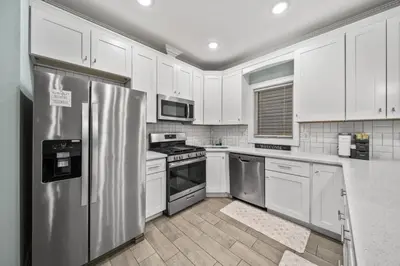 a kitchen with white cabinets and a stainless steel refrigerator at Skyline Haven Luxe NYC Escape in Jersey City