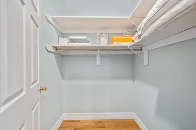 a hallway with white walls and a white closet with shelves at Skyline Haven Luxe NYC Escape in Jersey City