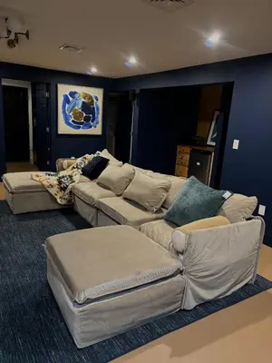 a living room with a couch and a ottoman at Waterfront Secluded Log Cabin in Beach Lake
