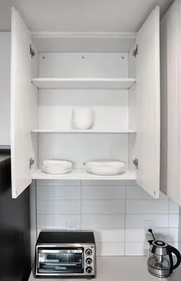 a kitchen with white cabinets with plates and a microwave at Midtown View - Minutes to City in Hoboken