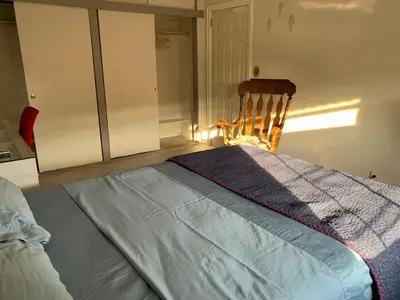 a bedroom with a bed and a wooden chair at Cheerful 2 BED ROOMS Apartment in heart of Queens in Jackson Heights