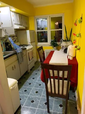 a kitchen with a table and chairs and yellow walls at Cheerful 2 BED ROOMS Apartment in heart of Queens in Jackson Heights