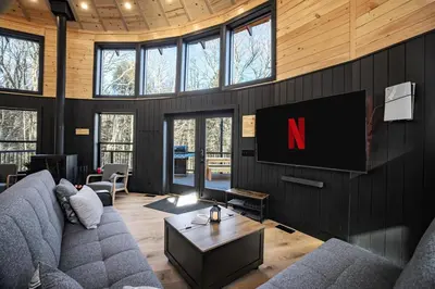 a living room with a couch and a tv at Mount Snow Yurt - Hot Tub, Wood Stove, WiFi, EVcharger in Dover