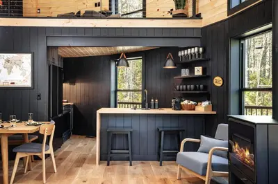 a kitchen with black walls and a table and chairs at Mount Snow Yurt - Hot Tub, Wood Stove, WiFi, EVcharger in Dover