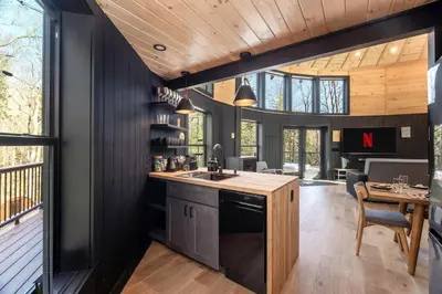 a kitchen with black walls and a wooden ceiling at Mount Snow Yurt - Hot Tub, Wood Stove, WiFi, EVcharger in Dover