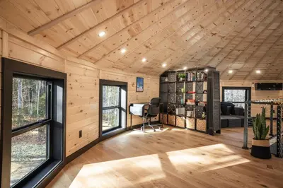 a room with wood paneled walls and a room with a desk at Mount Snow Yurt - Hot Tub, Wood Stove, WiFi, EVcharger in Dover