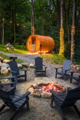 a tent in the woods with chairs and a fire at Mount Snow Yurt - Hot Tub, Wood Stove, WiFi, EVcharger in Dover