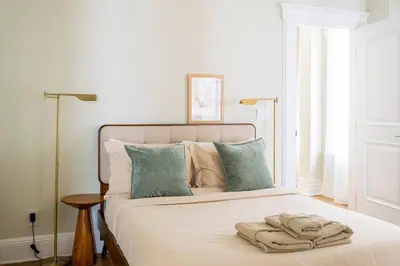 a bedroom with a bed with white sheets and blue pillows at Bright & Modern - 35 Mins to NYC - Extended Stays in Jersey City