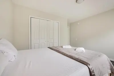 a white bedroom with a large bed with two towels on it at Spacious 5BR Home In Heart Of Poconos By Camelback Skiing Swimming Lake in Tobyhanna