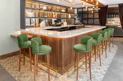 a bar with green bar stools in a restaurant at voco Astoria by IHG in New York