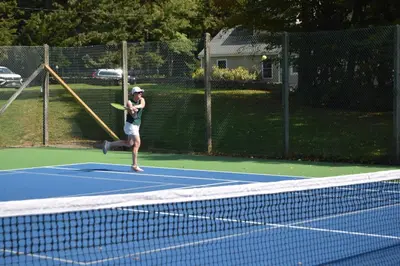 a woman hitting a tennis ball on a tennis court at Vermont Retreat with private pool and tennis court in Wilmington